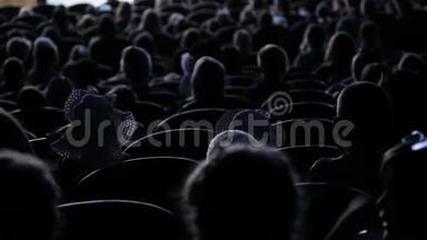 观众为剧院的演出或演讲鼓掌。 后面的视频。 儿童和成人